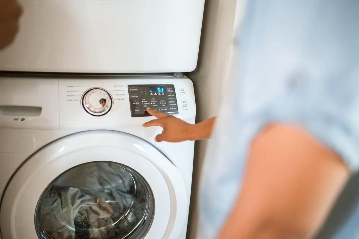 Main qui choisit un programme sur le panneau d'une machine à laver